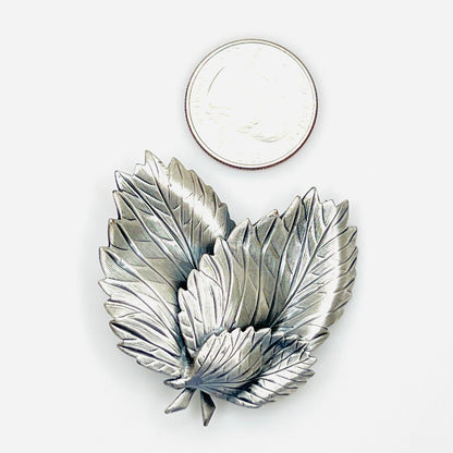 Silver tone layered leaf brooch shown beside quarter for scale