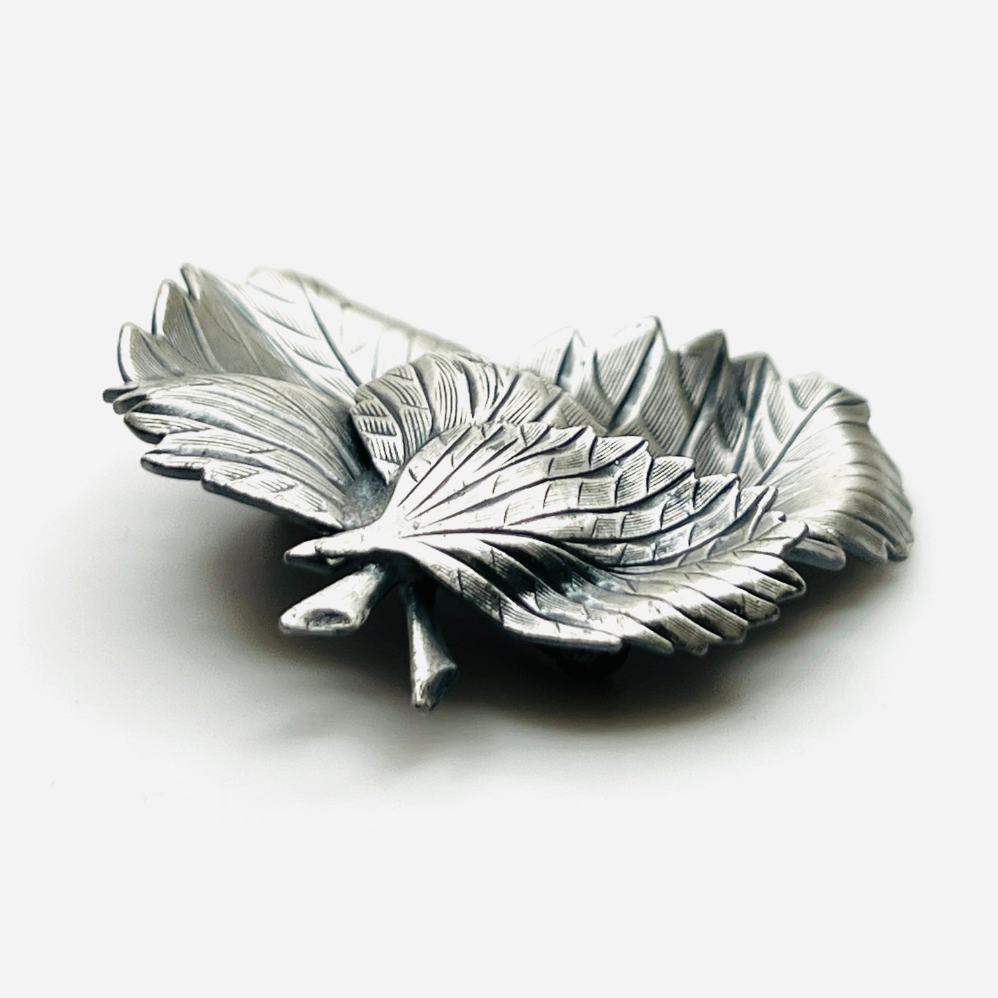 Side profile of vintage sculptural three leaf brooch in aged silver tone