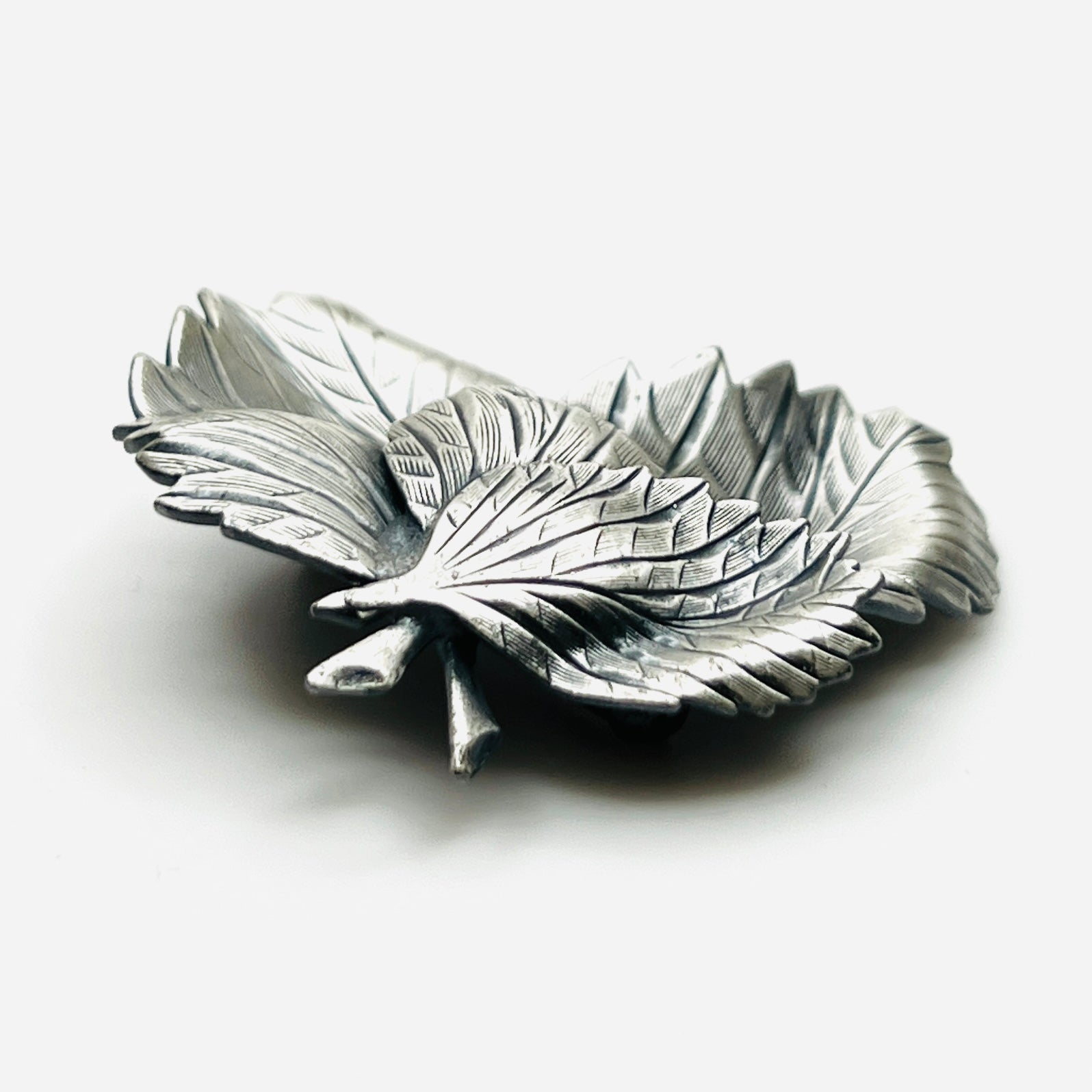 Side profile of vintage sculptural three leaf brooch in aged silver tone