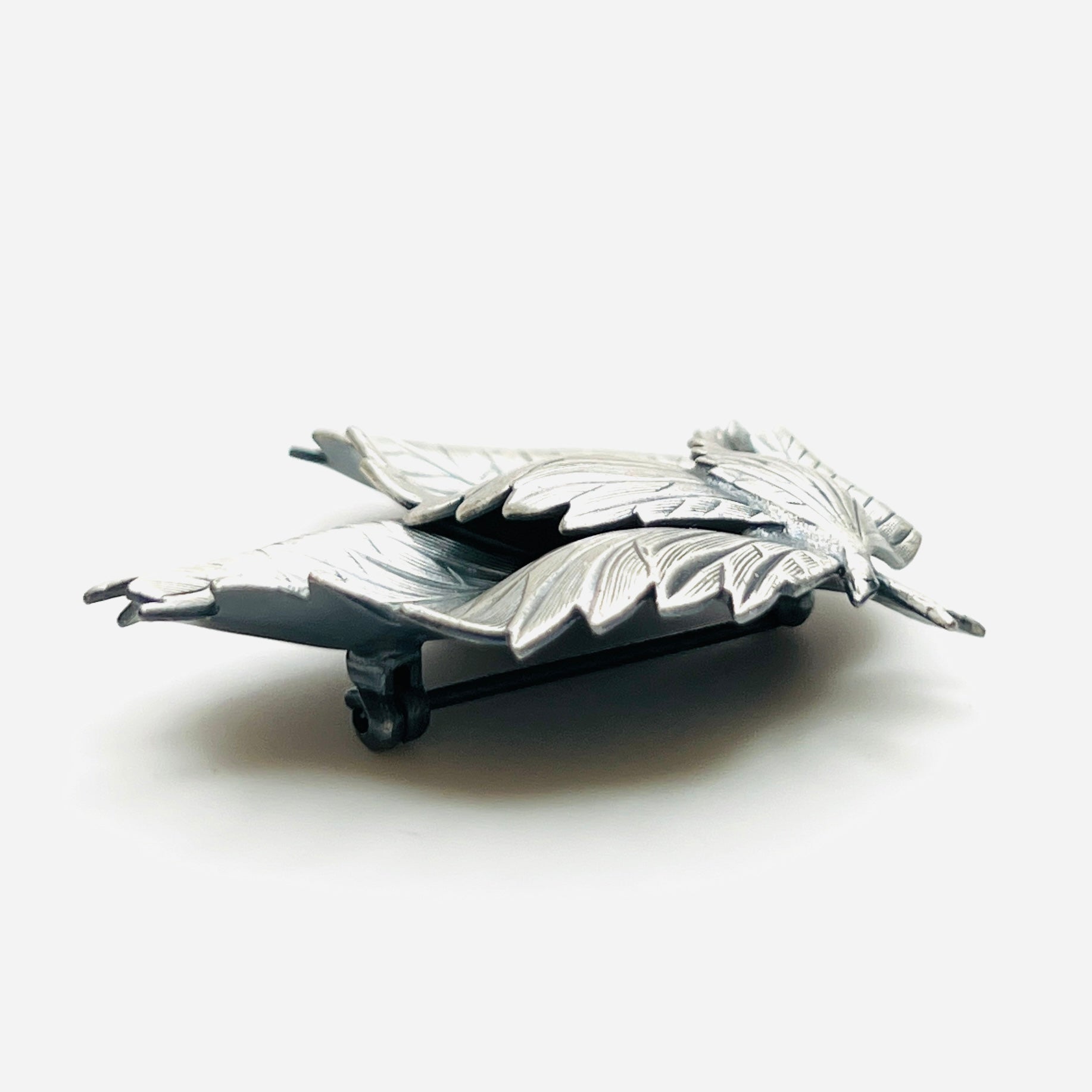 Side profile of vintage sculptural three leaf brooch in aged silver tone