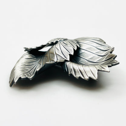 Side profile of vintage sculptural three leaf brooch in aged silver tone