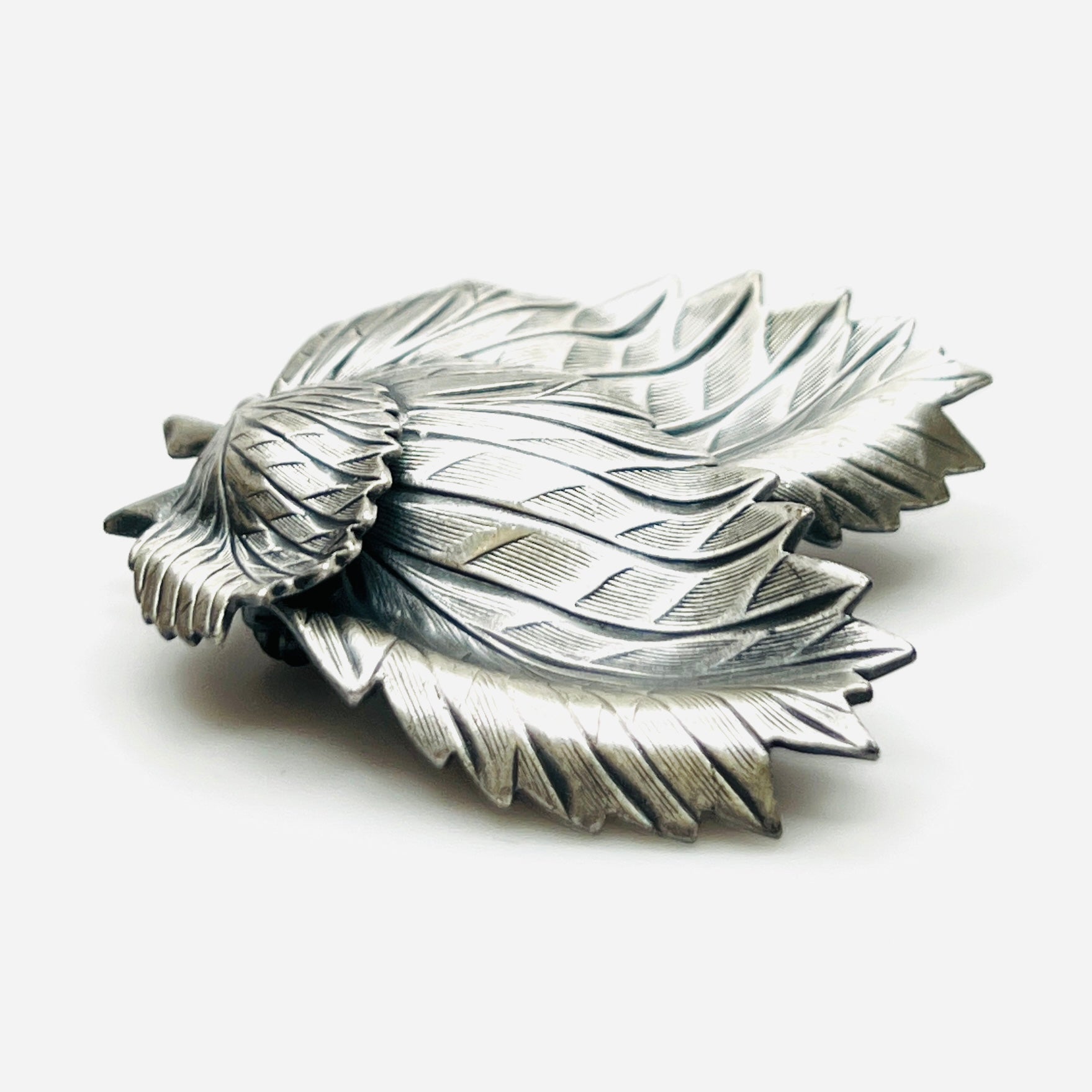 Side profile of vintage sculptural three leaf brooch in aged silver tone