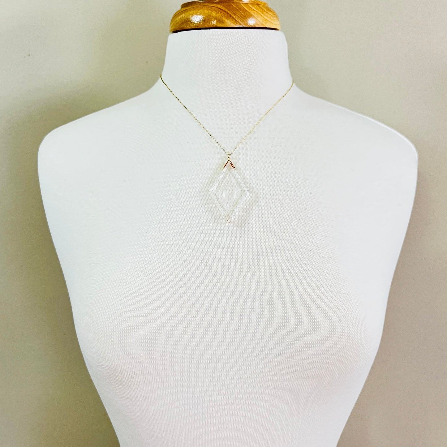 Necklace worn on mannequin showing large clear intaglio pendant