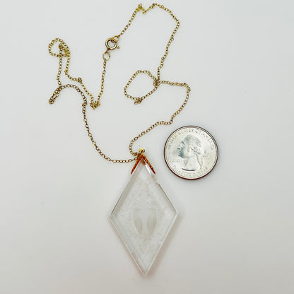 Close-up of crystal love birds pendant next to coin for scale
