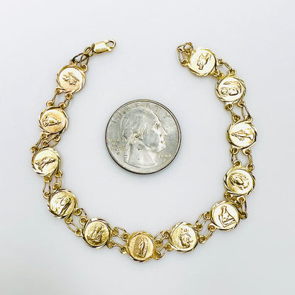 14K gold religious medal bracelet with Catholic saint panels beside quarter for scale