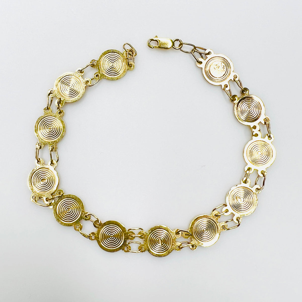 Reverse of vintage 14K gold saints bracelet showing concentric medal backs