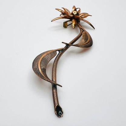 Side profile of vintage copper flower brooch showing raised petals and sculptural curved leaves