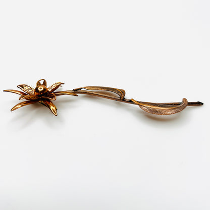 Side profile of vintage copper flower brooch showing raised petals and sculptural curved leaves