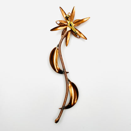 Reverse of 1970s copper-tone flower brooch showing long stem, metal construction and rollover clasp