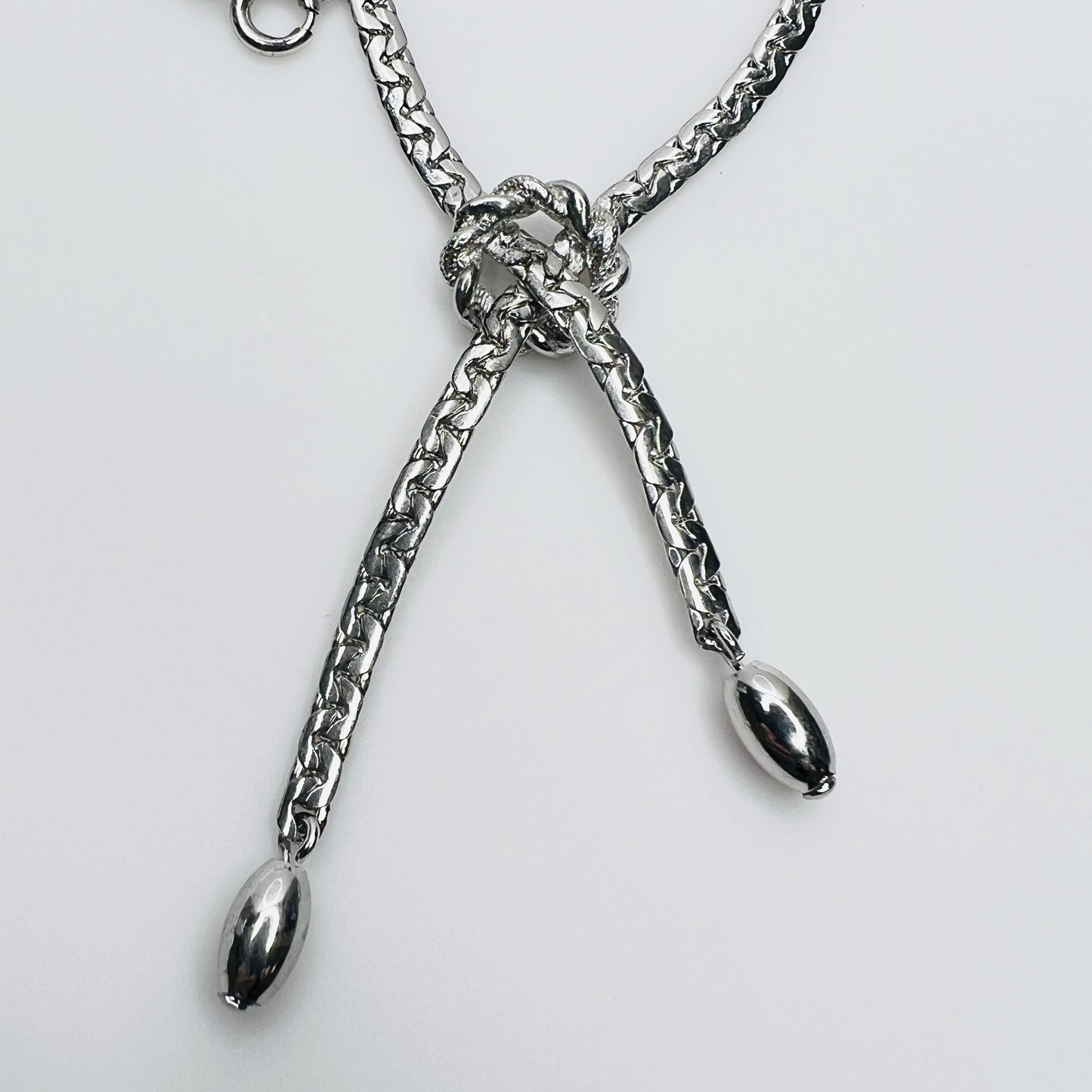 Close-up of knotted center and drop ends in silver tone