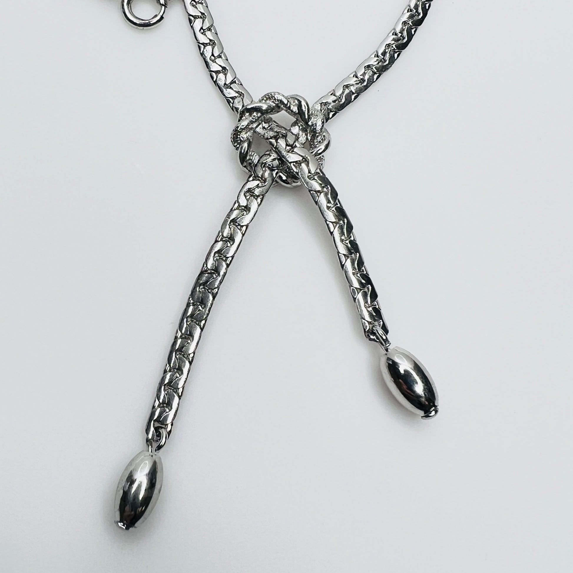 Close-up of knotted center and drop ends in silver tone