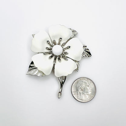 Large Sarah Coventry white enamel flower brooch shown beside quarter for scale