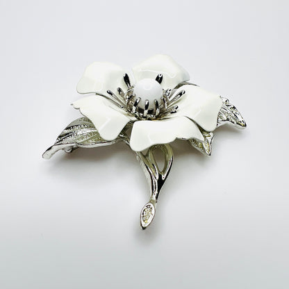 Side view of white enamel flower brooch showing dimensional petals, center and silver-tone leaves