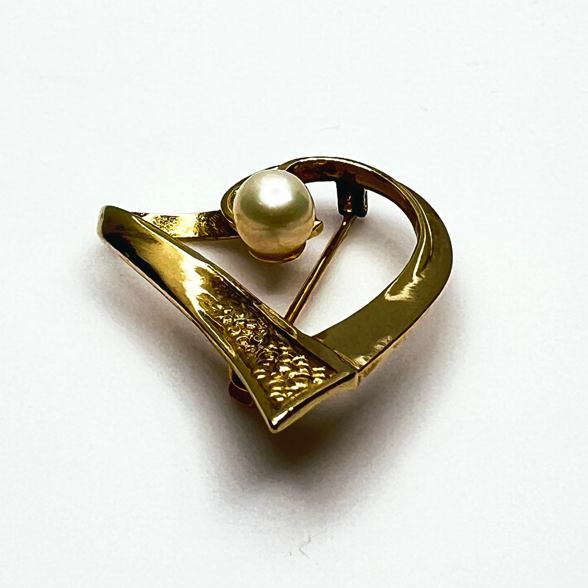 Side view of vintage sterling silver vermeil heart pin showing dimensional ribbon construction, textured detailing and raised pearl.