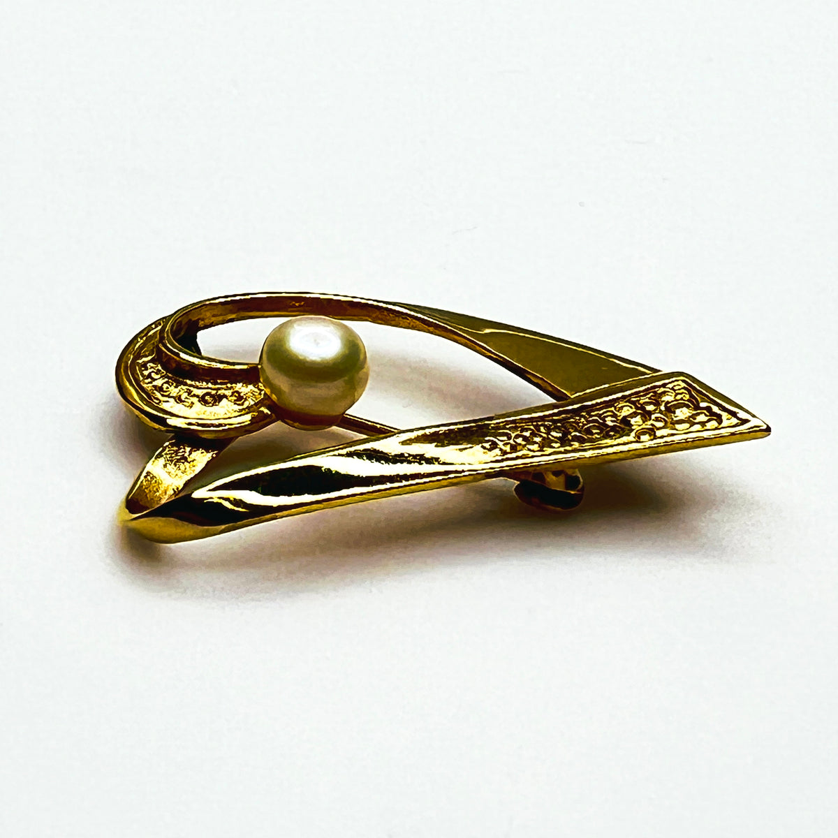Side view of vintage sterling silver vermeil heart pin showing dimensional ribbon construction, textured detailing and raised pearl.