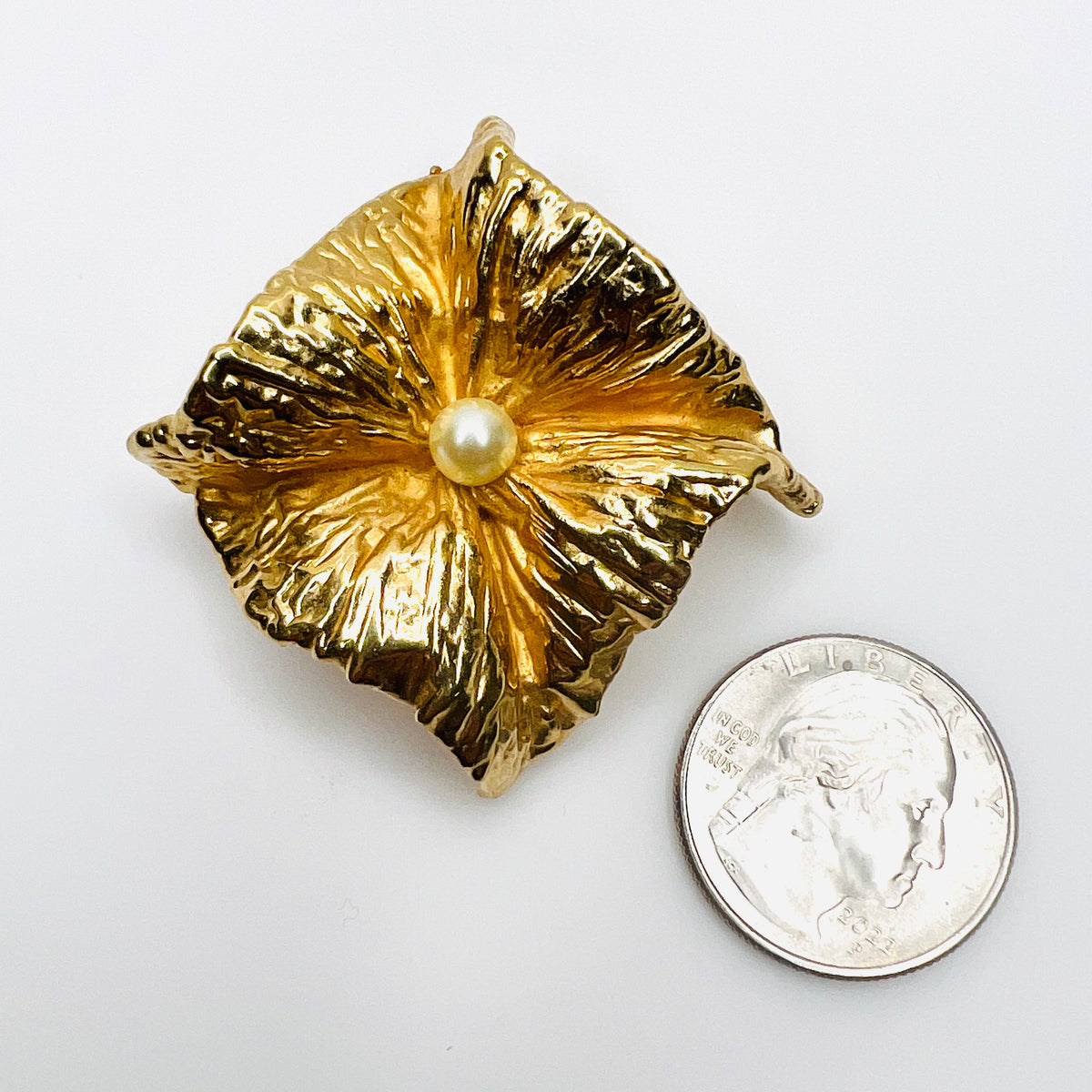 Signed Napier gold-tone faux pearl brooch beside a quarter showing its substantial 2-inch square design.