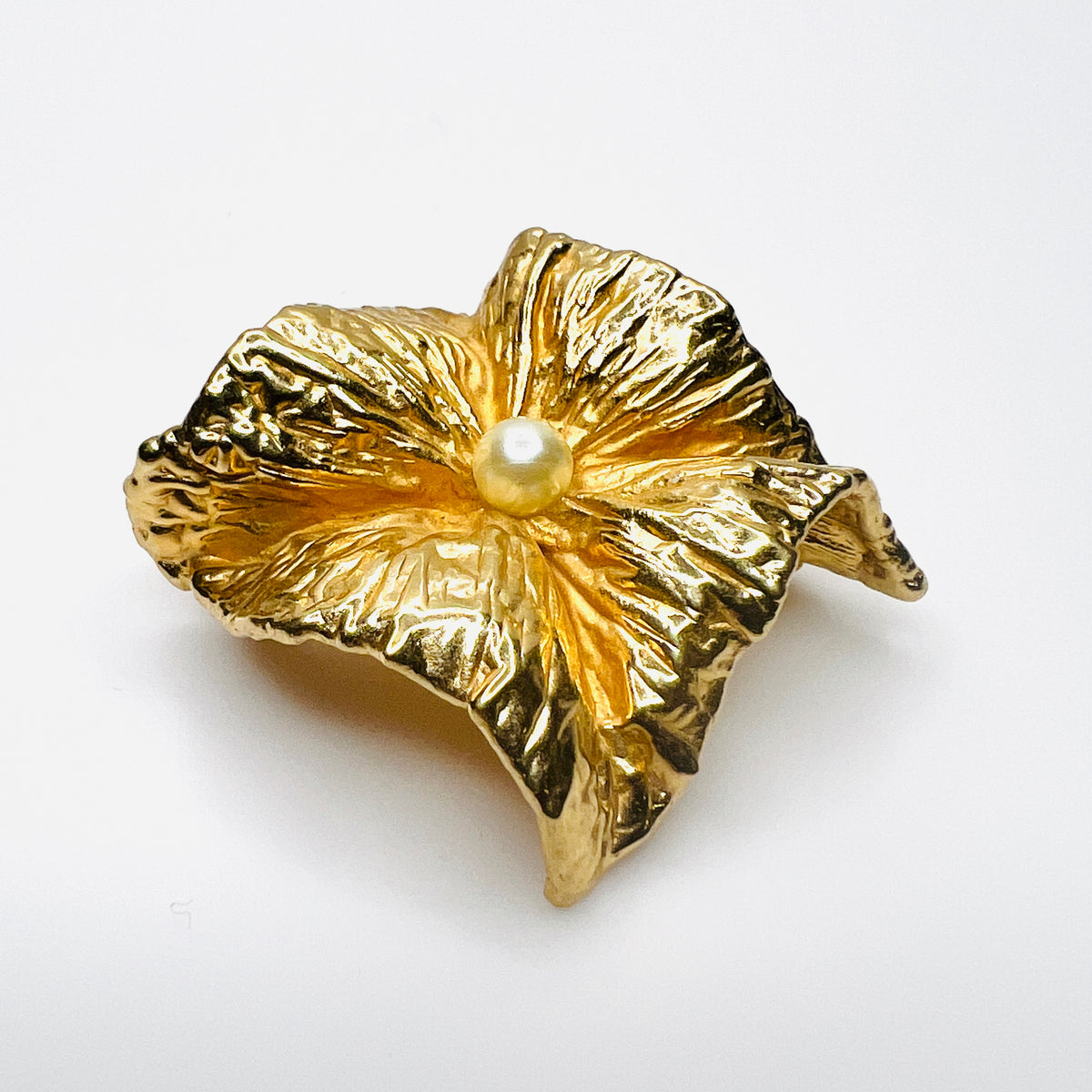 Angled side view of vintage Napier brooch showing deeply sculpted gold-tone folds, dimensional construction, and faux pearl center.