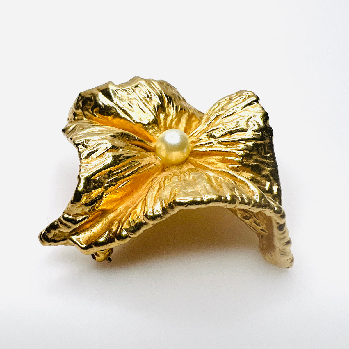 Angled side view of vintage Napier brooch showing deeply sculpted gold-tone folds, dimensional construction, and faux pearl center.