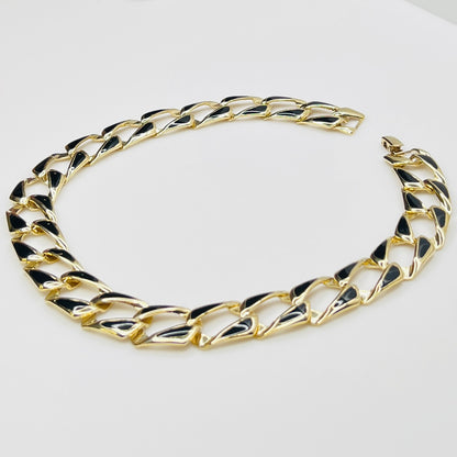 Close-up side view of oversized gold tone links with black enamel inlays.