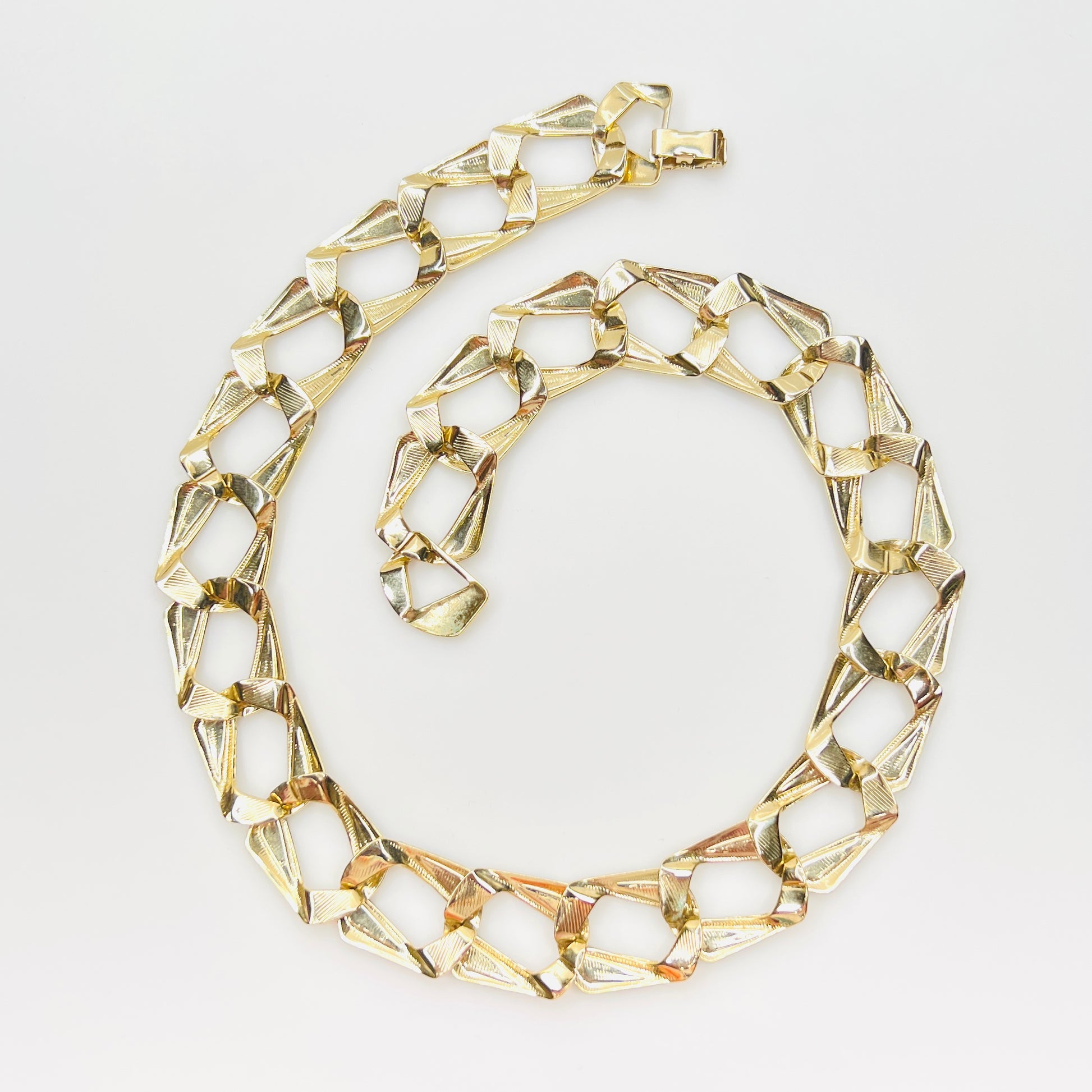 Back view of oversized gold tone links with black enamel inlays.