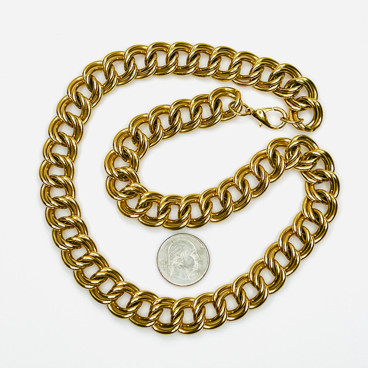 Full view of vintage 1980s gold-tone chain necklace with substantial interlocking double links, lobster clasp, and quarter for scale.