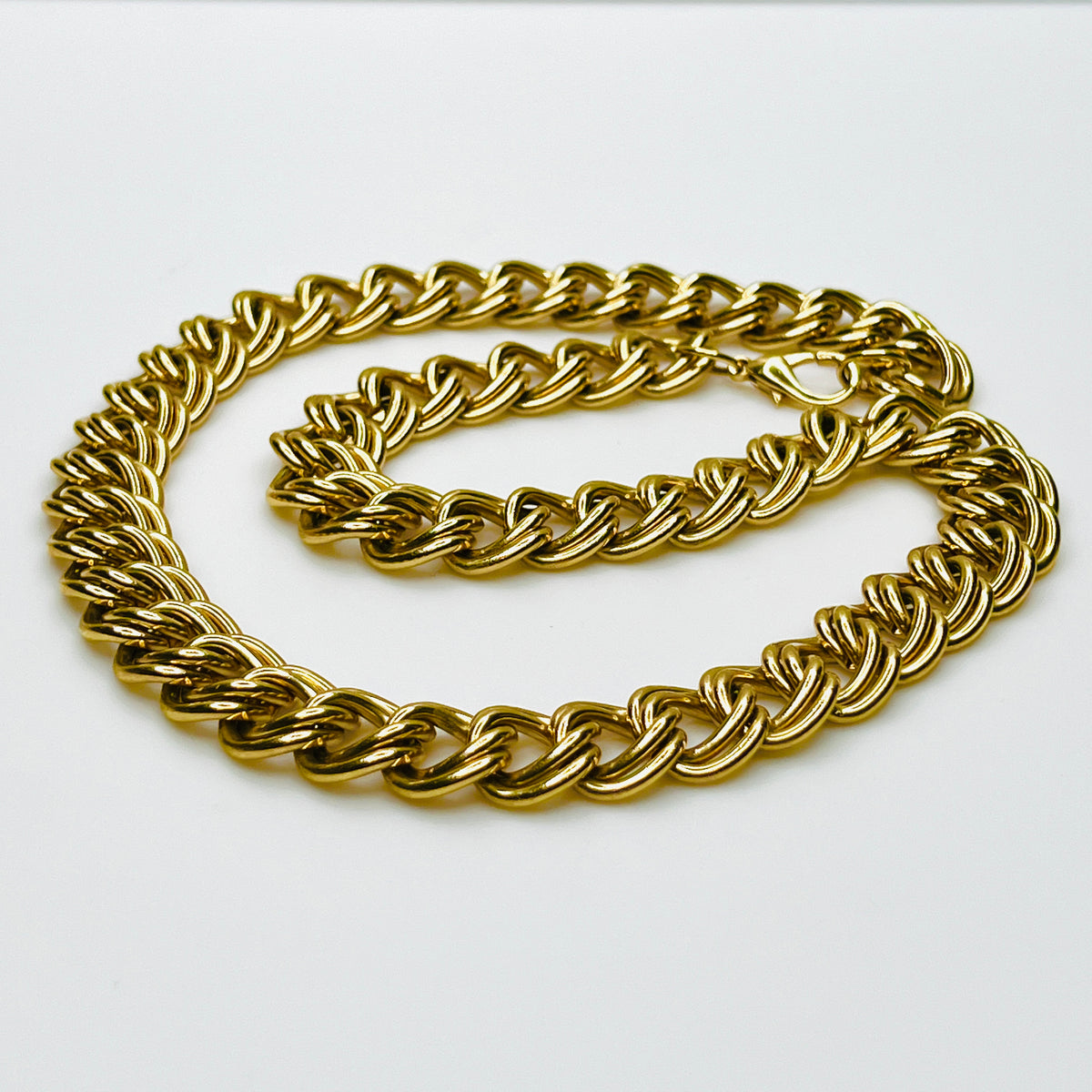 Close-up of vintage chunky gold-tone necklace showing polished, dimensional double links and substantial chain construction.