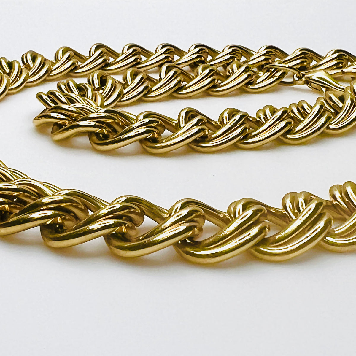 Close-up of vintage chunky gold-tone necklace showing polished, dimensional double links and substantial chain construction.