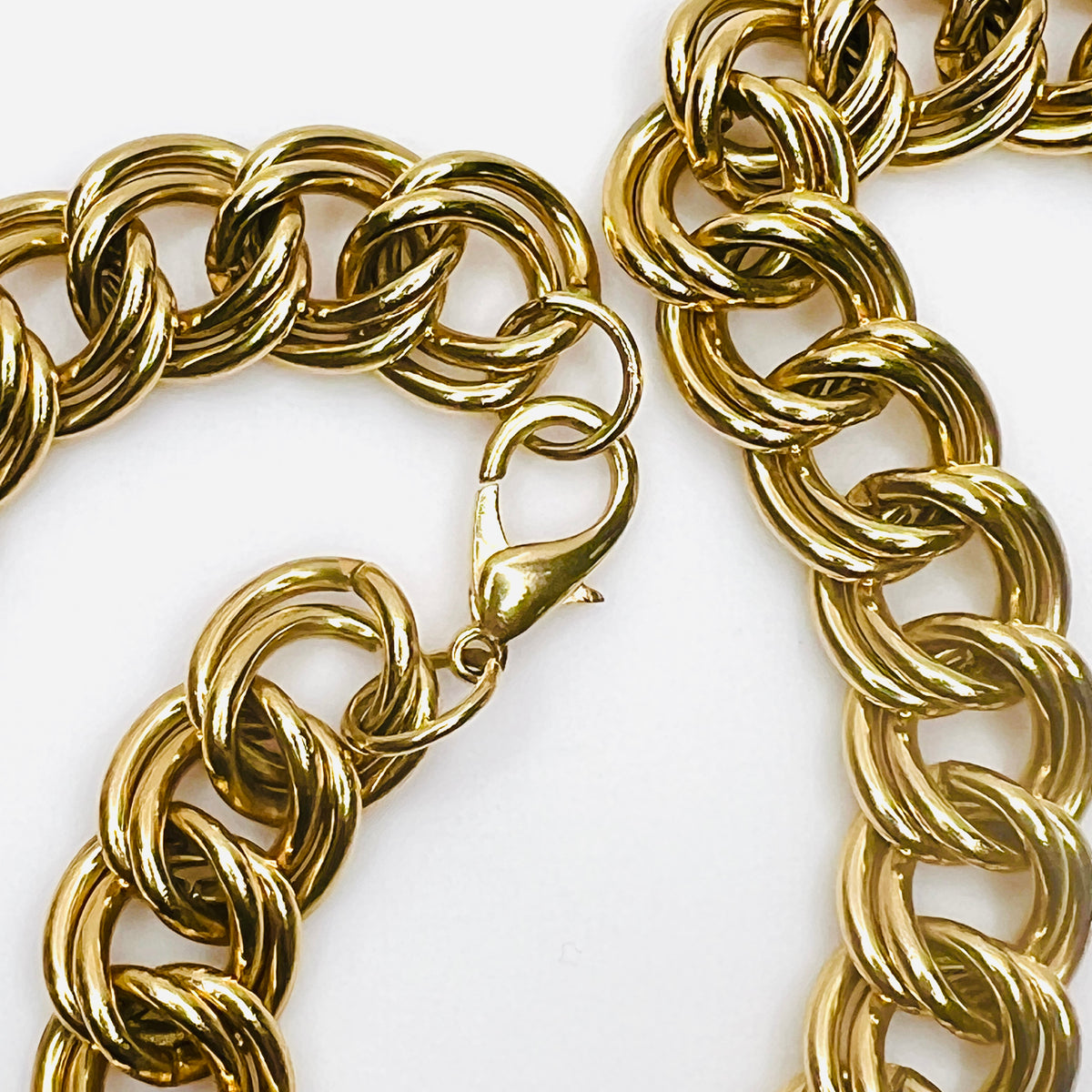 Detailed close-up of large gold-tone lobster claw clasp and interlocking double-link construction on vintage statement necklace.
