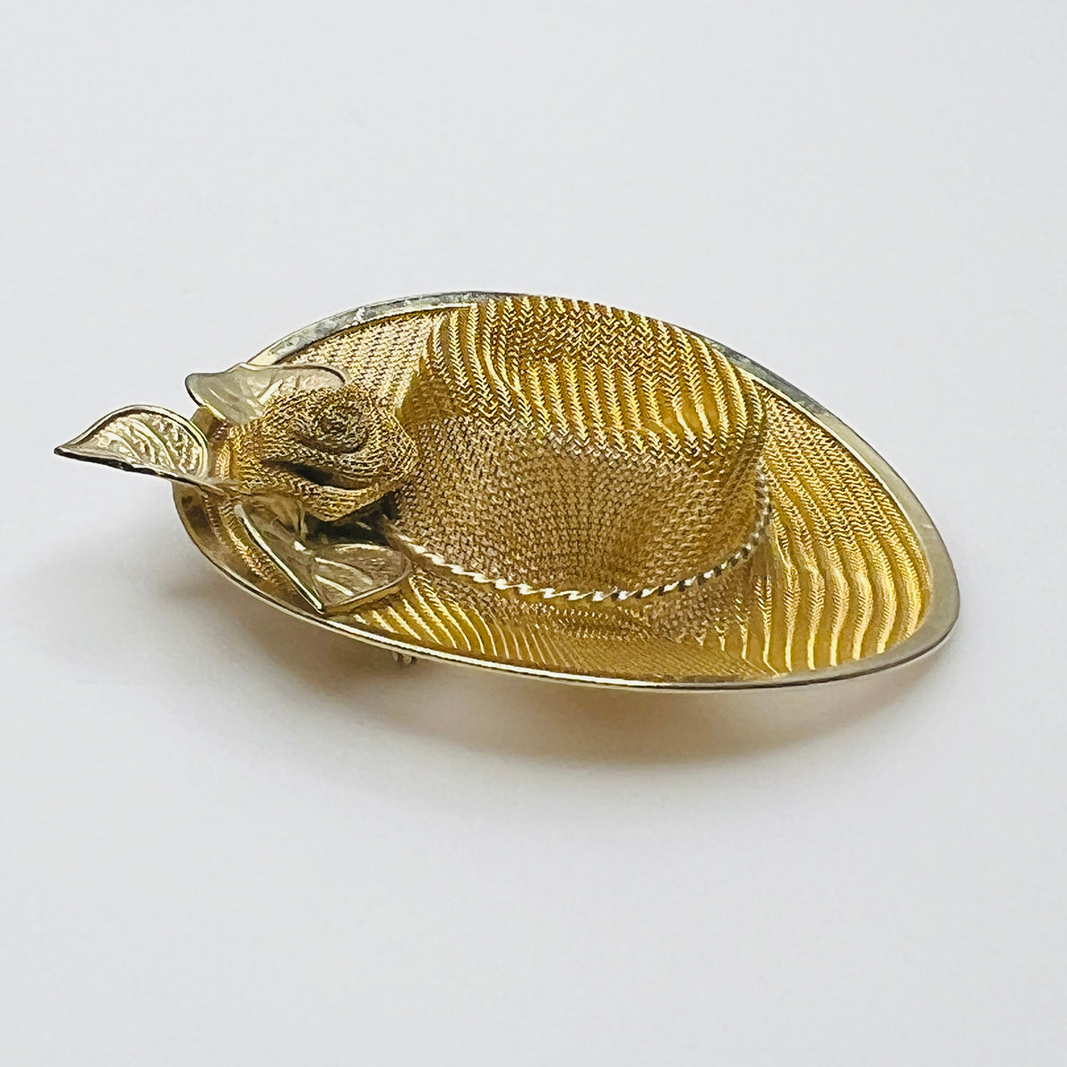 Side view of vintage gold-tone mesh hat pin showing dimensional crown, wide brim and rose embellishment