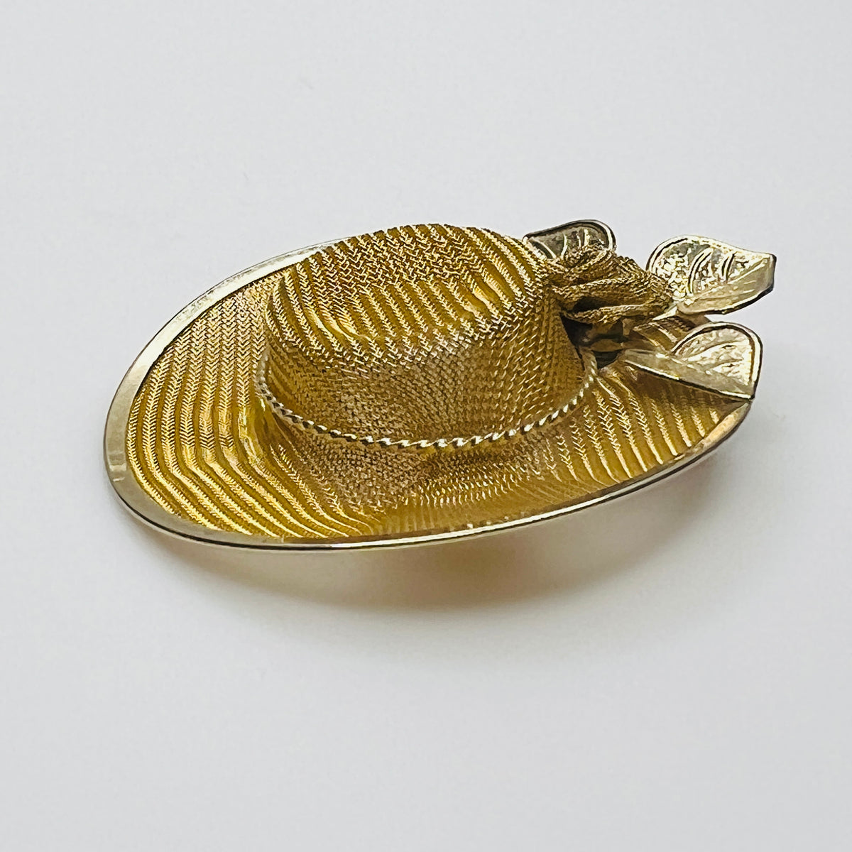 Side view of vintage gold-tone mesh hat pin showing dimensional crown, wide brim and rose embellishment