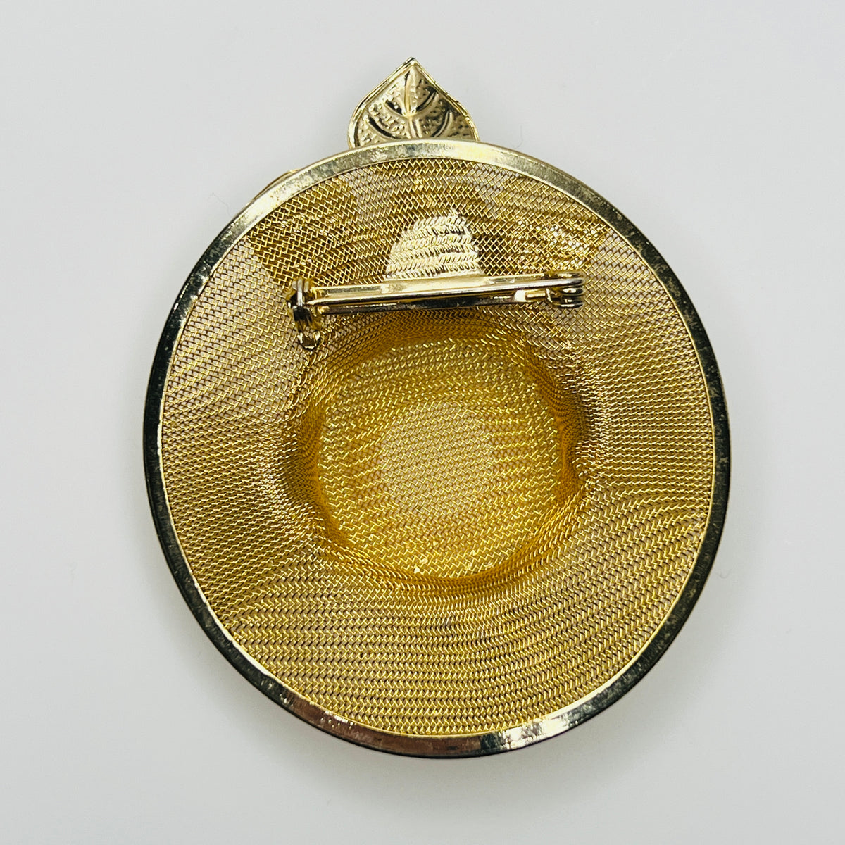 Reverse of 1980s gold mesh hat brooch showing woven metal construction and rollover safety clasp