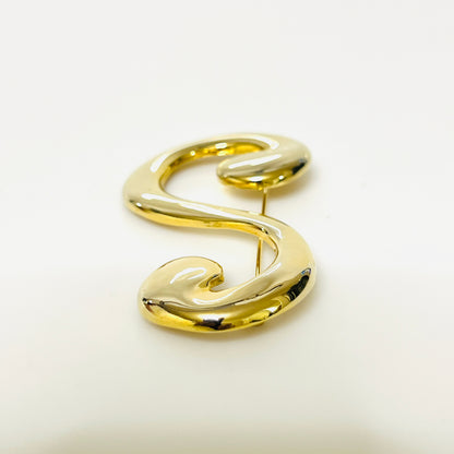 Side view of gold-tone letter S brooch showing its raised rounded profile and polished finish.
