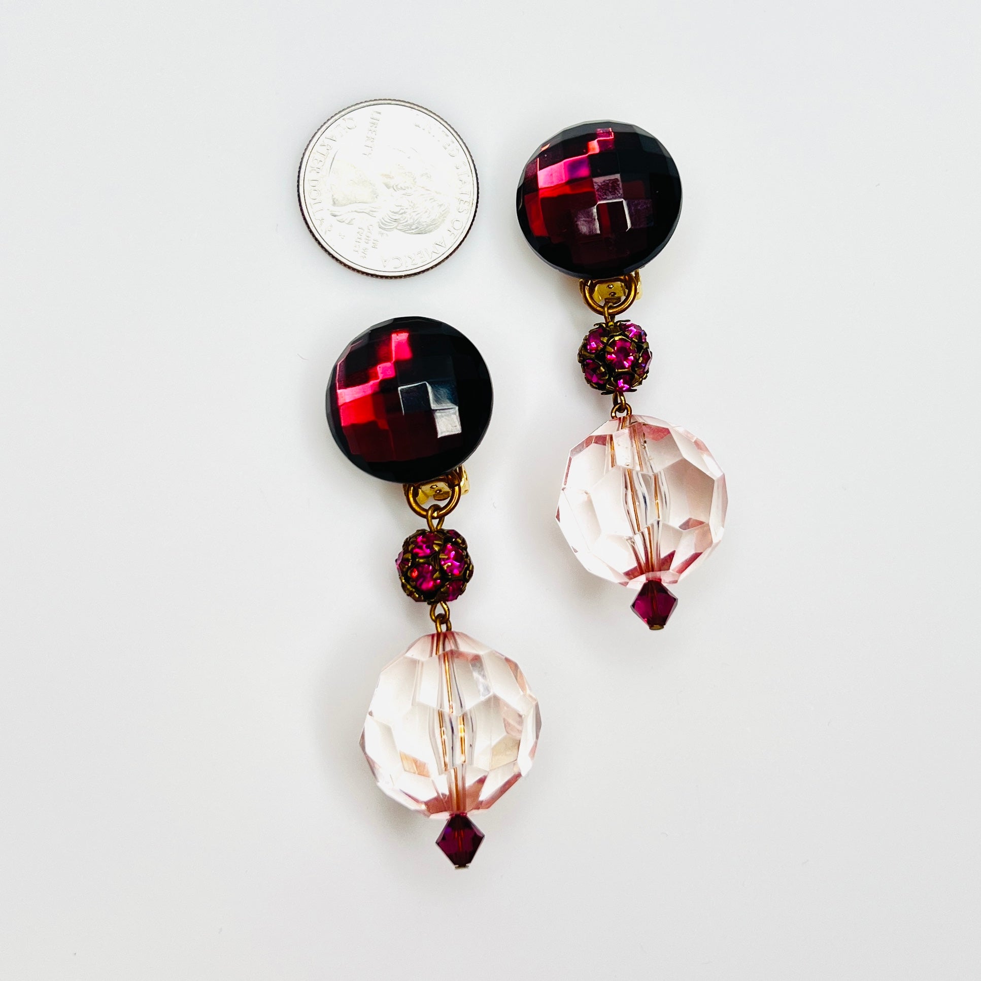 Oversized vintage pink clip-on earrings beside quarter showing faceted acrylic beads and rhinestone accents.