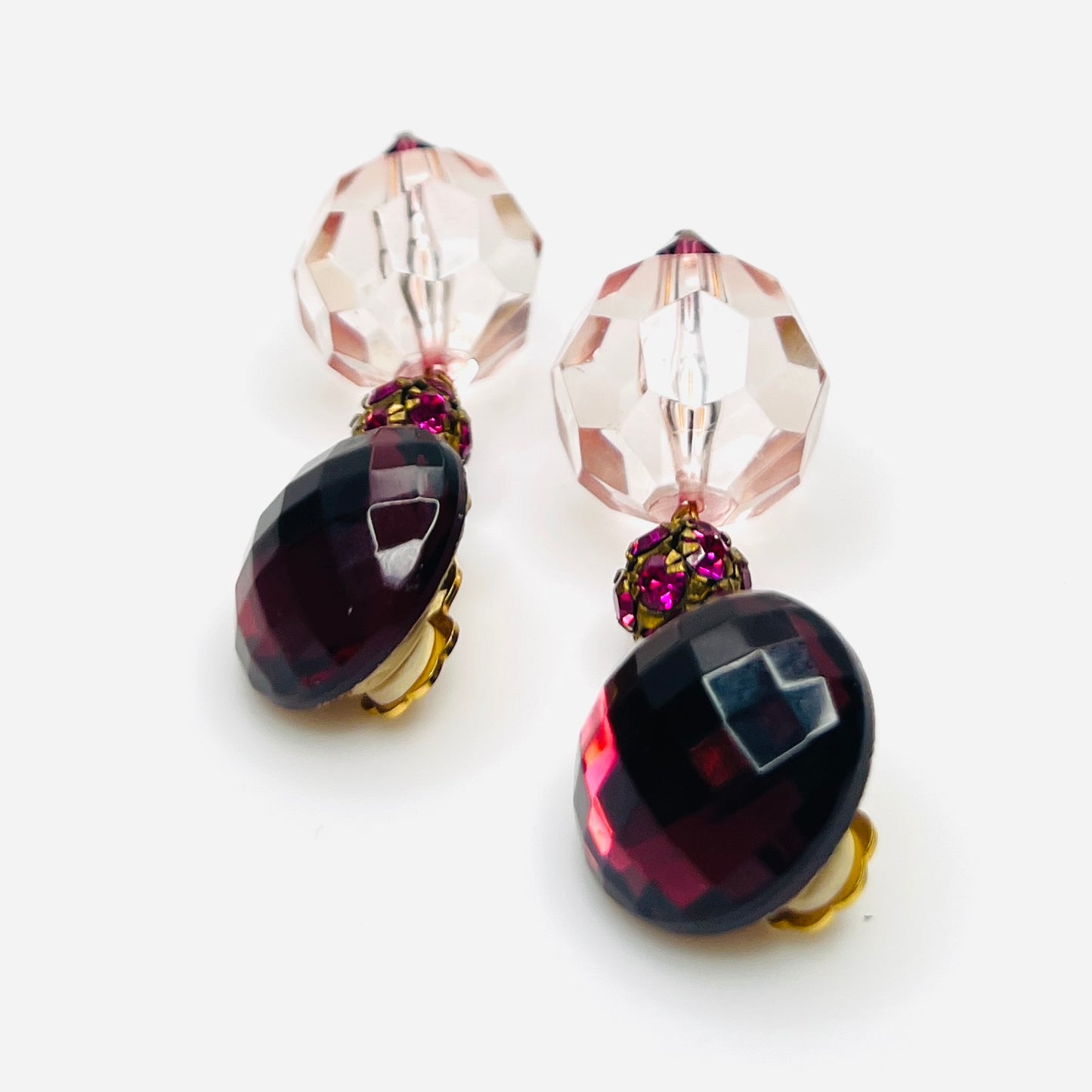side view of vintage 1980s acrylic clip-on earrings with faceted pink beads and gold-tone hardware.