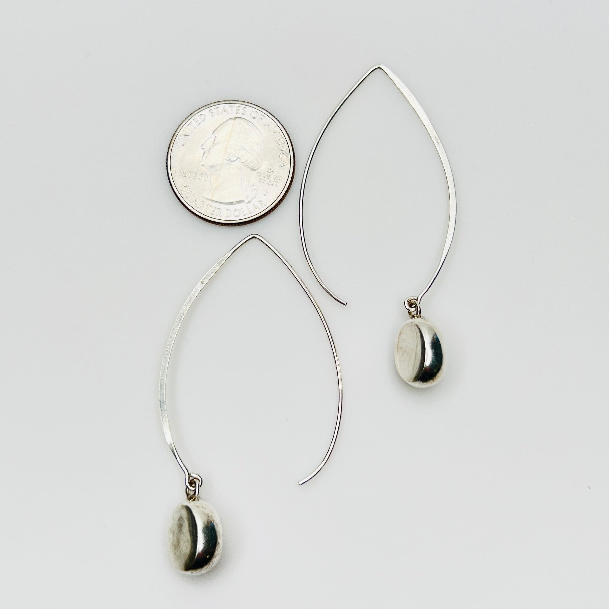 Sterling silver modernist drop earrings beside quarter for size comparison