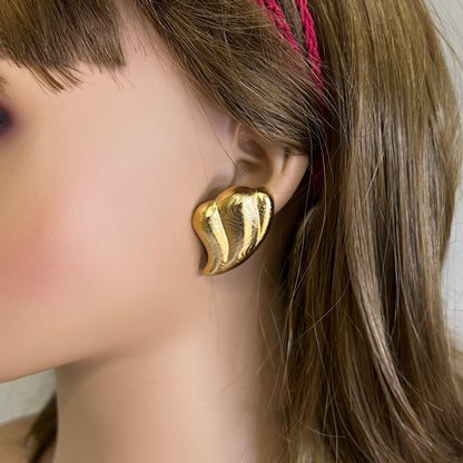 Oversized gold tone abstract wave earrings worn on mannequin ear