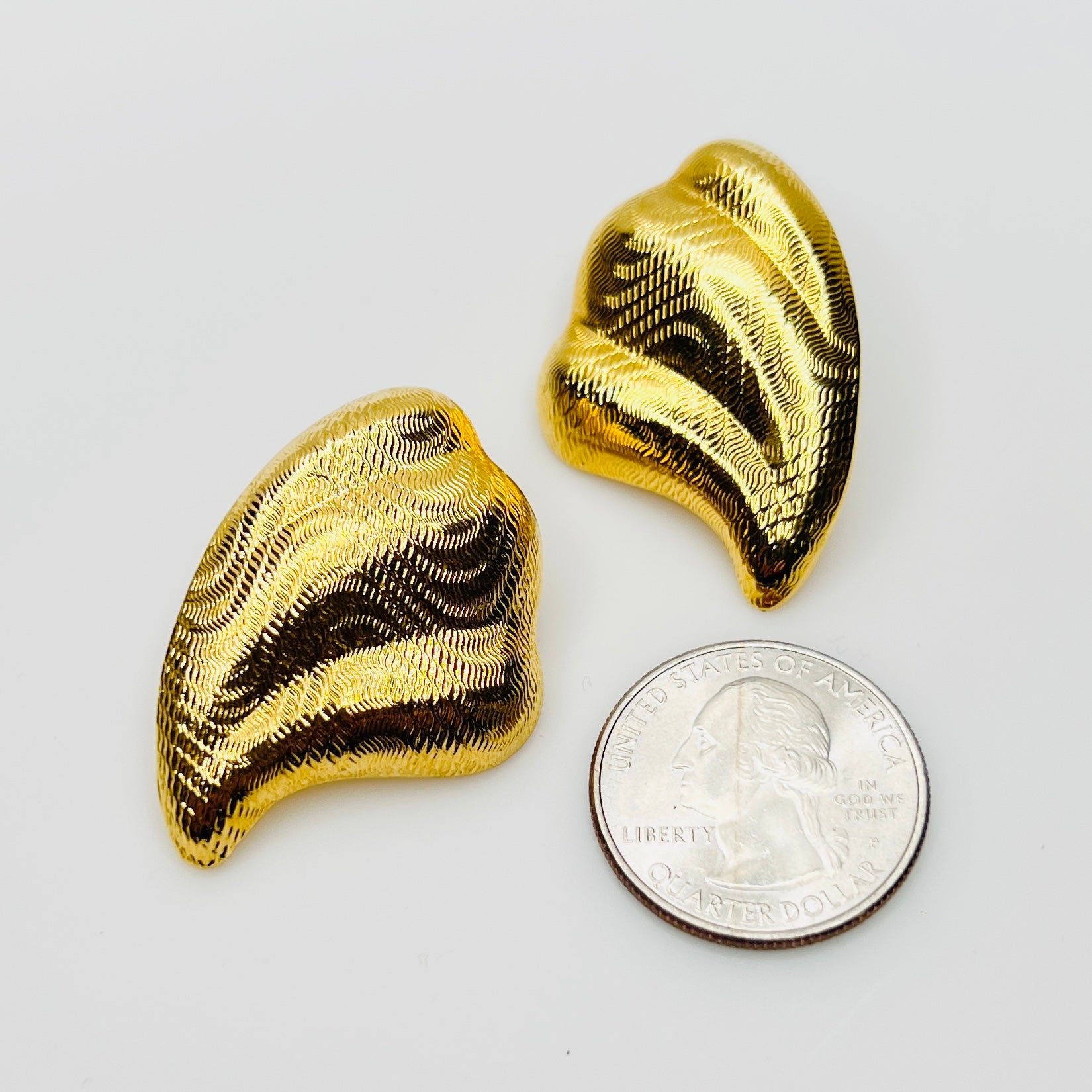 Vintage sculptural gold stud earrings beside quarter for size comparison