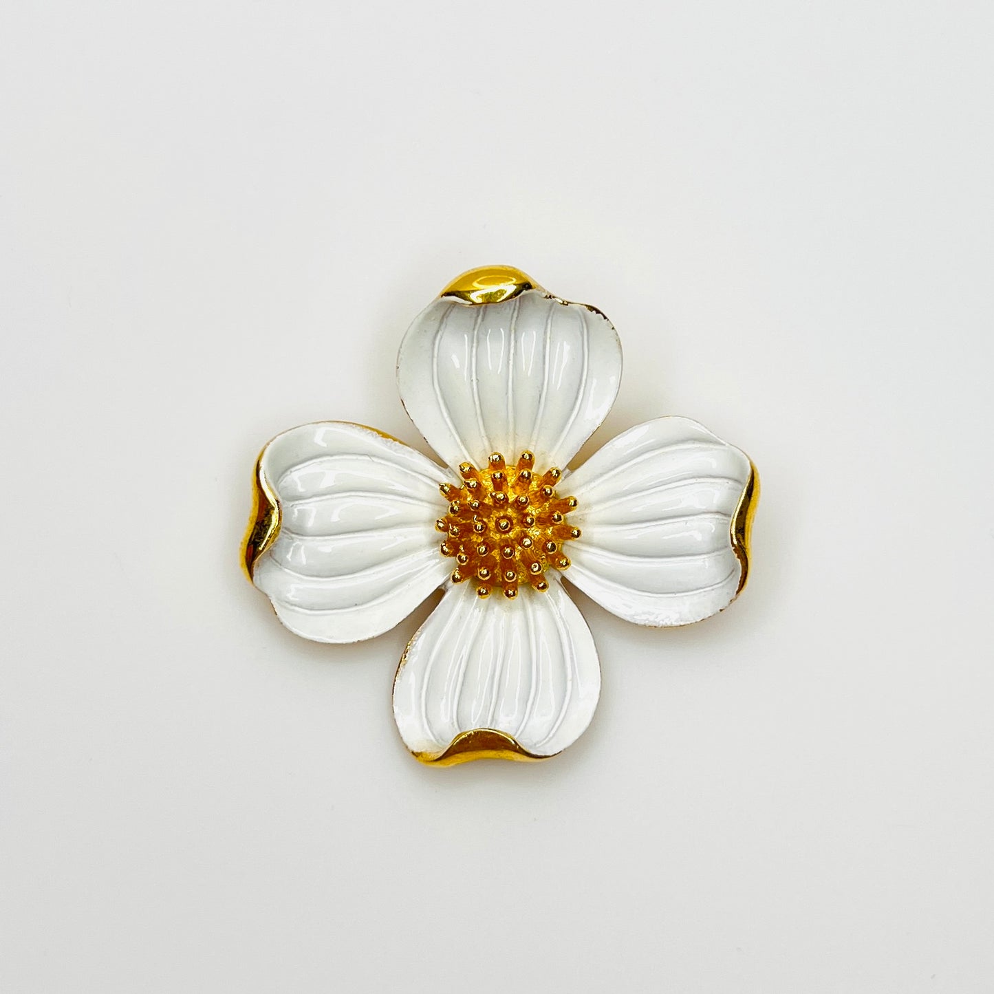 Vintage Crown Trifari white enamel dogwood flower brooch with gold-tone accents.
