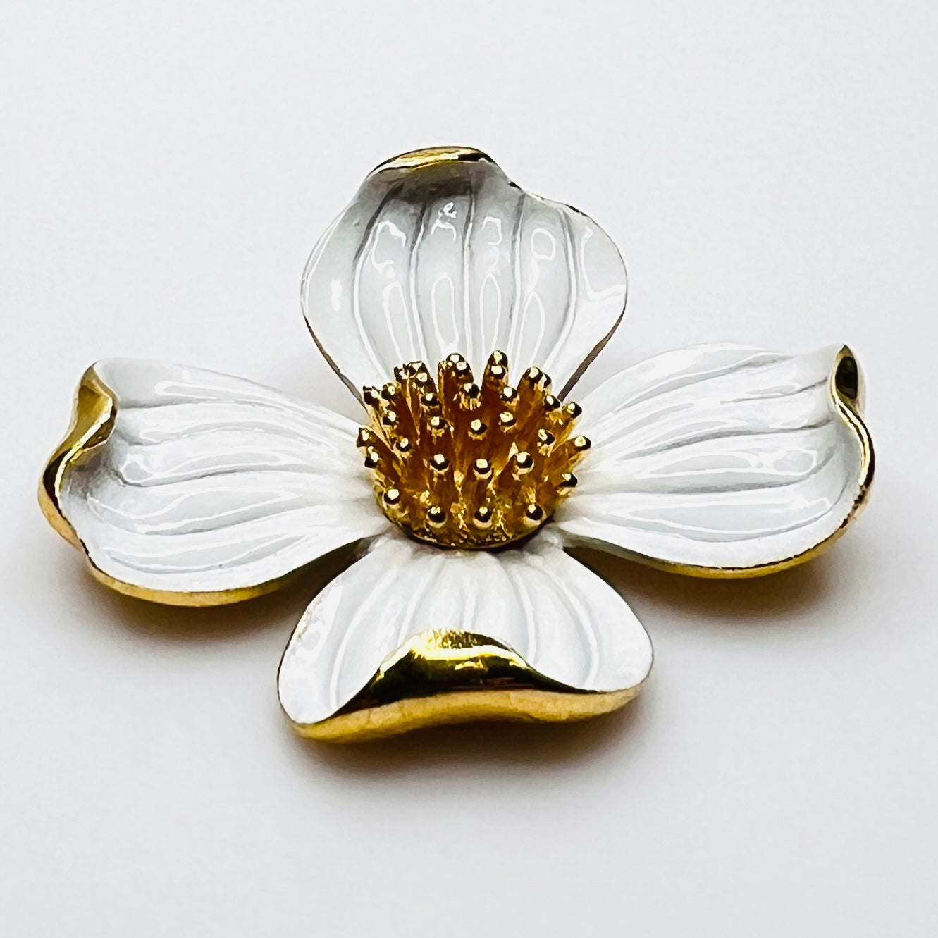 Side profile of vintage Trifari white enamel dogwood brooch showing dimensional petals.