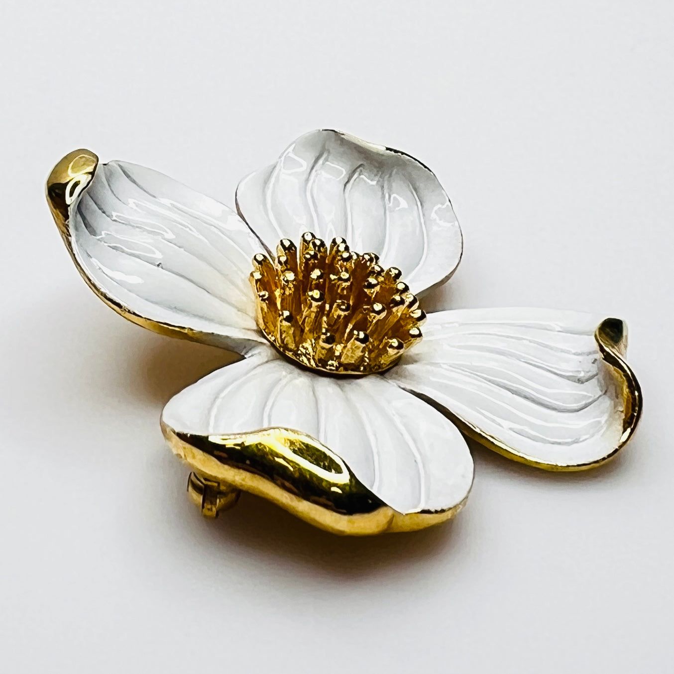 Side profile of vintage Trifari white enamel dogwood brooch showing dimensional petals.