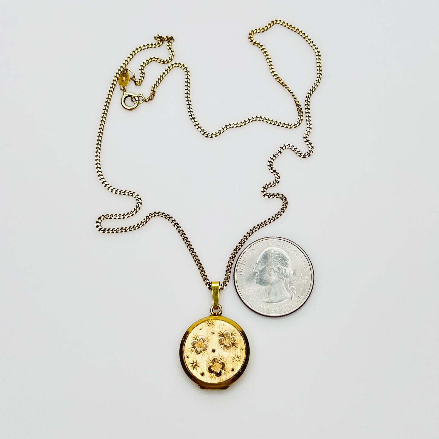 Close-up of engraved floral gold plated sterling silver round locket pendant