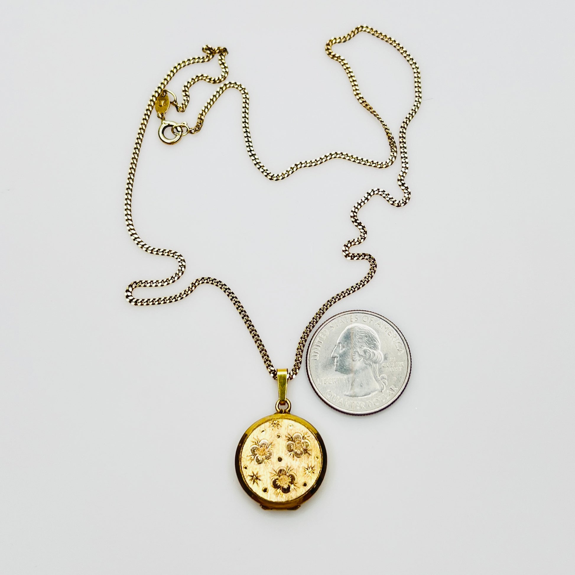 Close-up of engraved floral gold plated sterling silver round locket pendant
