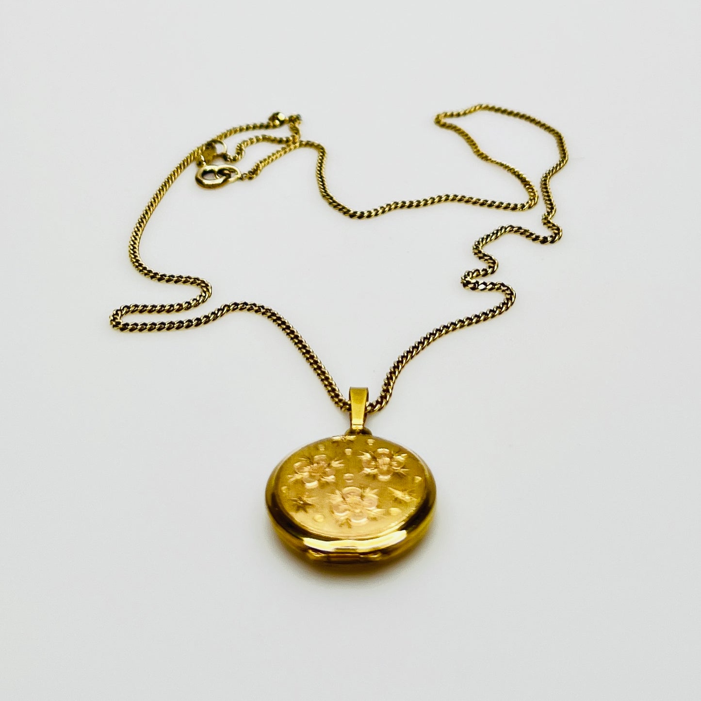 Close-up of engraved floral gold plated sterling silver round locket pendant