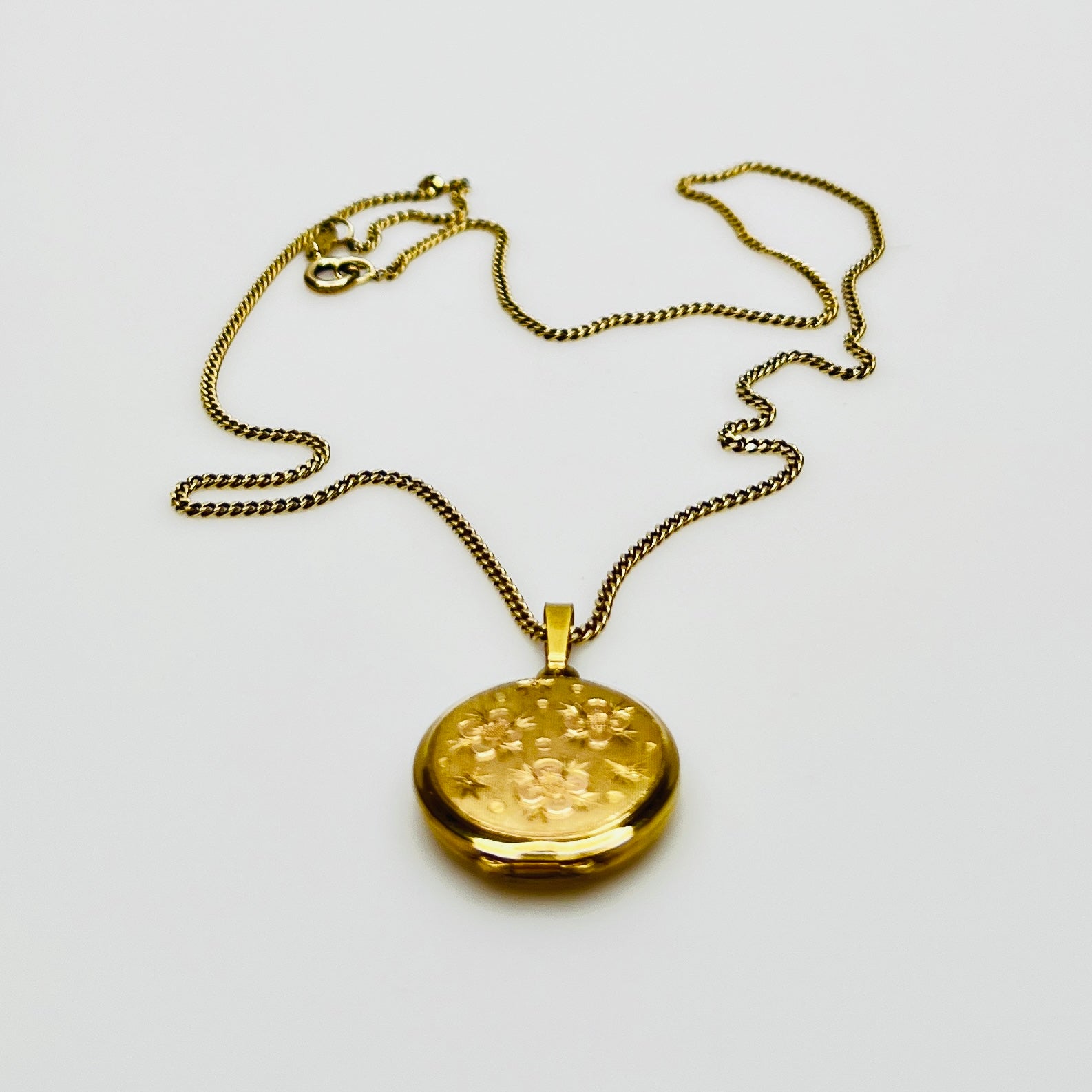 Close-up of engraved floral gold plated sterling silver round locket pendant