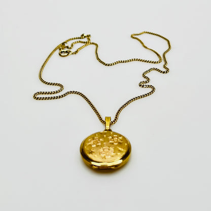 Close-up of engraved floral gold plated sterling silver round locket pendant