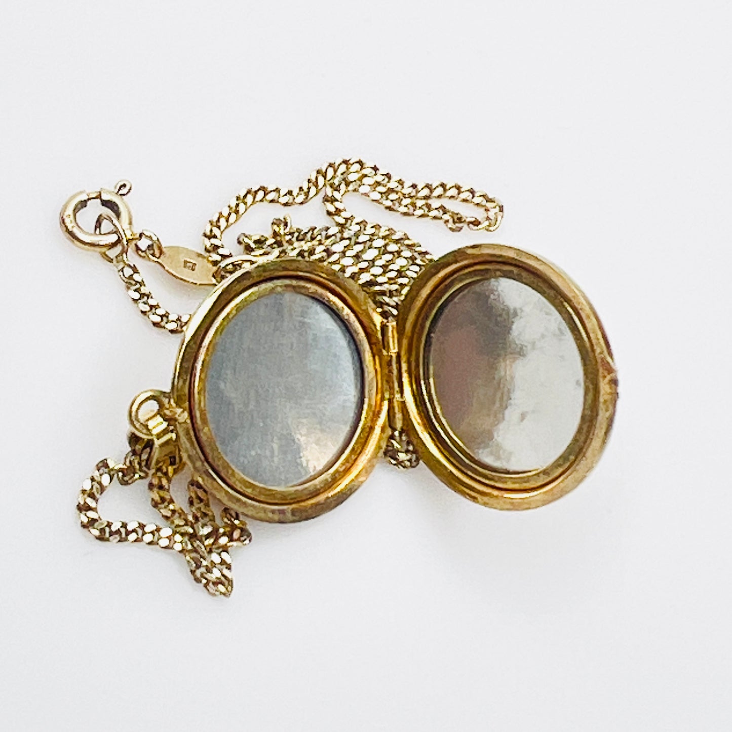Close-up of engraved floral gold plated sterling silver round locket pendant
