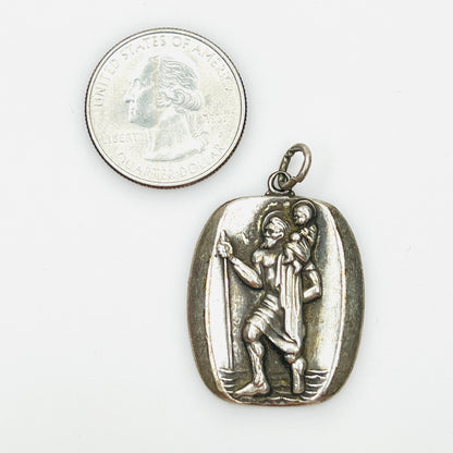 Signed sterling St. Christopher pendant beside quarter showing size and detailed relief.