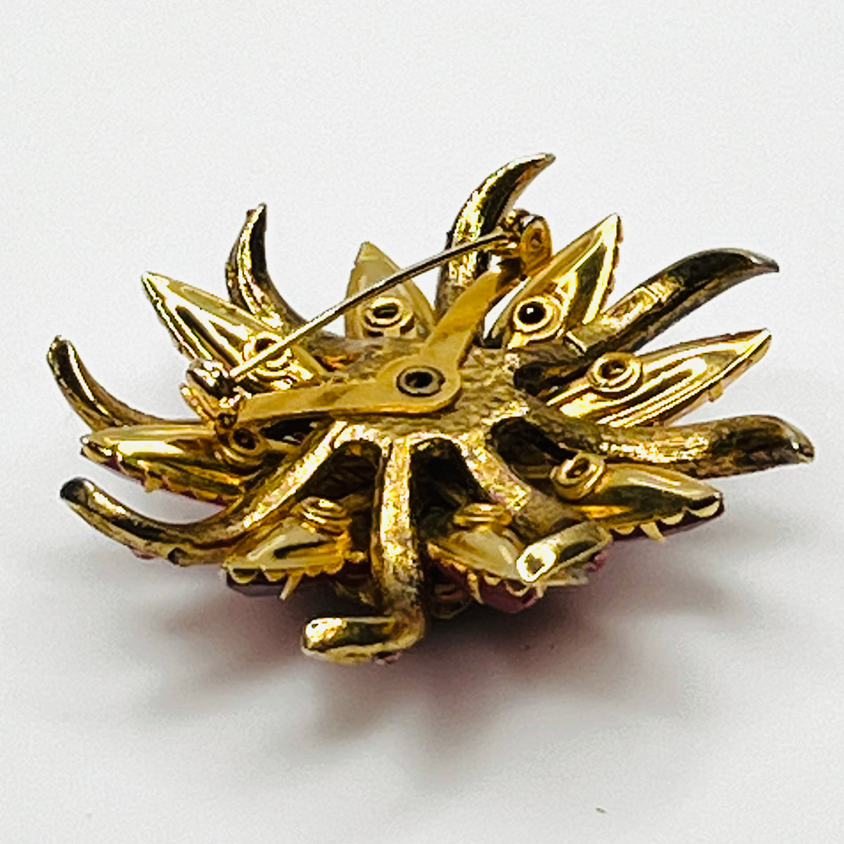 Side view of vintage Selro Selini floral brooch showing layered red, pink, and iridescent prong-set rhinestones.