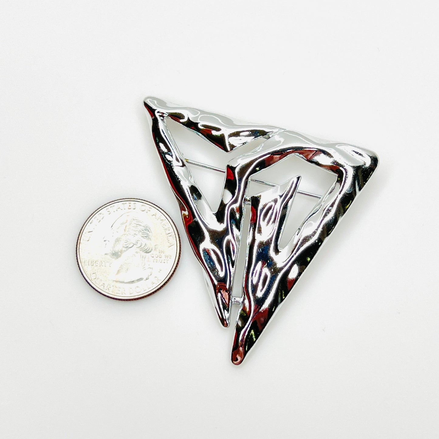Signed Torino Modernist silver-tone brooch beside a U.S. quarter for size reference.