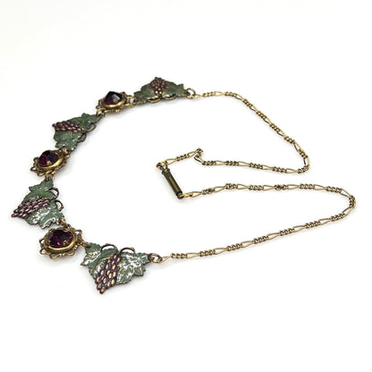 Side view of vintage enamel grape necklace with alternating rhinestone and leaf panels.